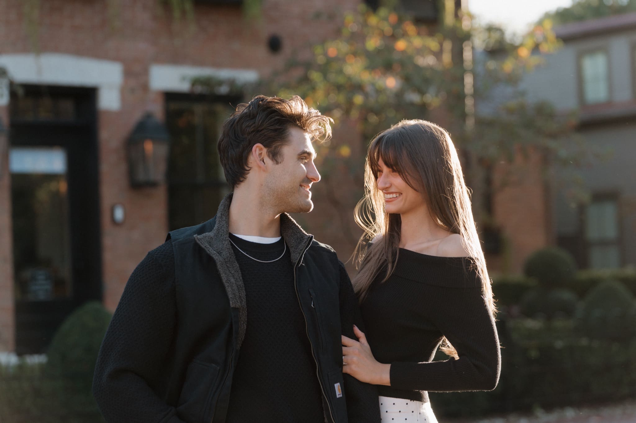Engaged couple smiling at each other in front of a brick townhouse in German Village, Columbus, Ohio