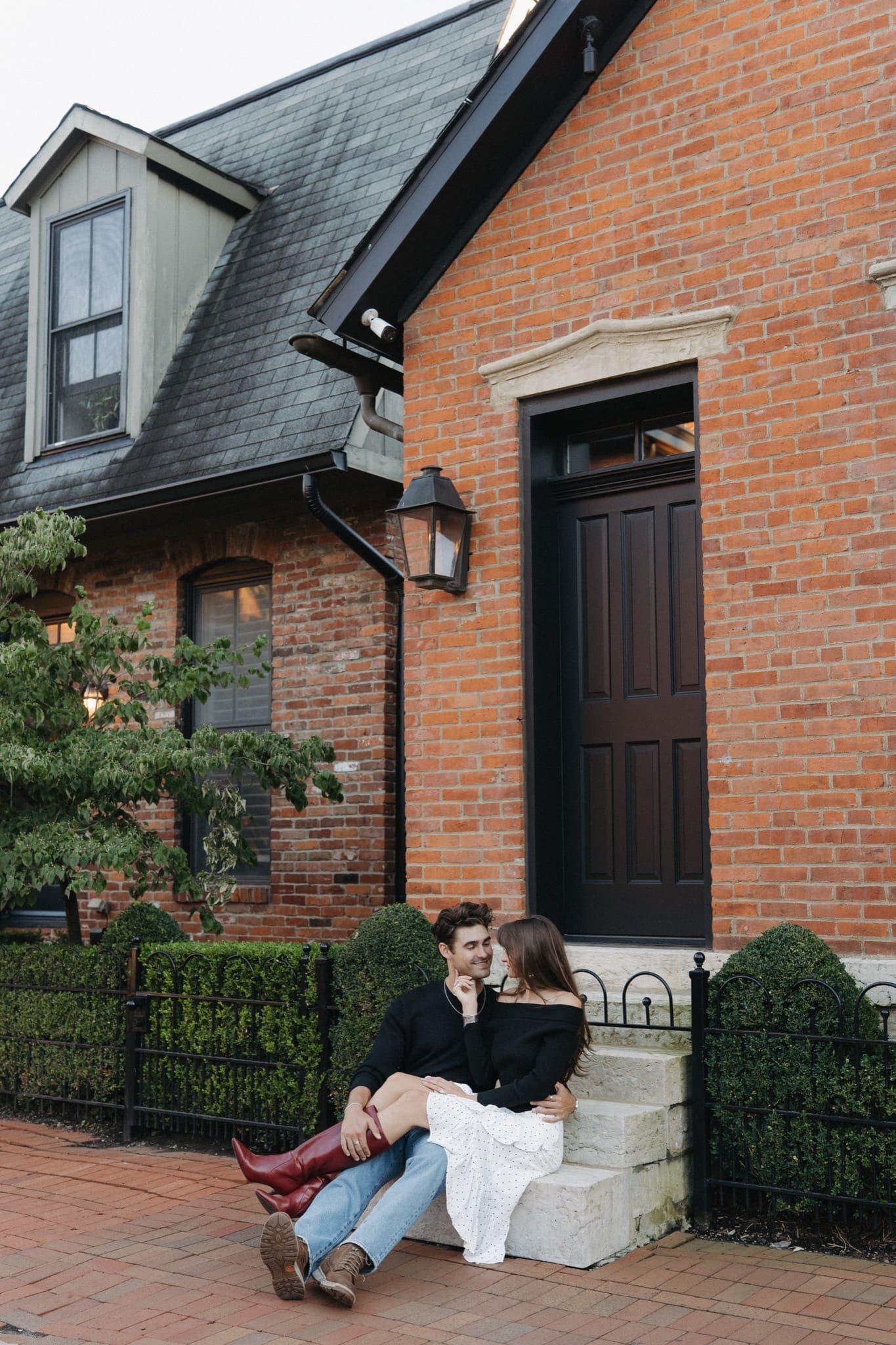 Engaged couple sitting on the steps of a historic brick home in German Village, Columbus, Ohio