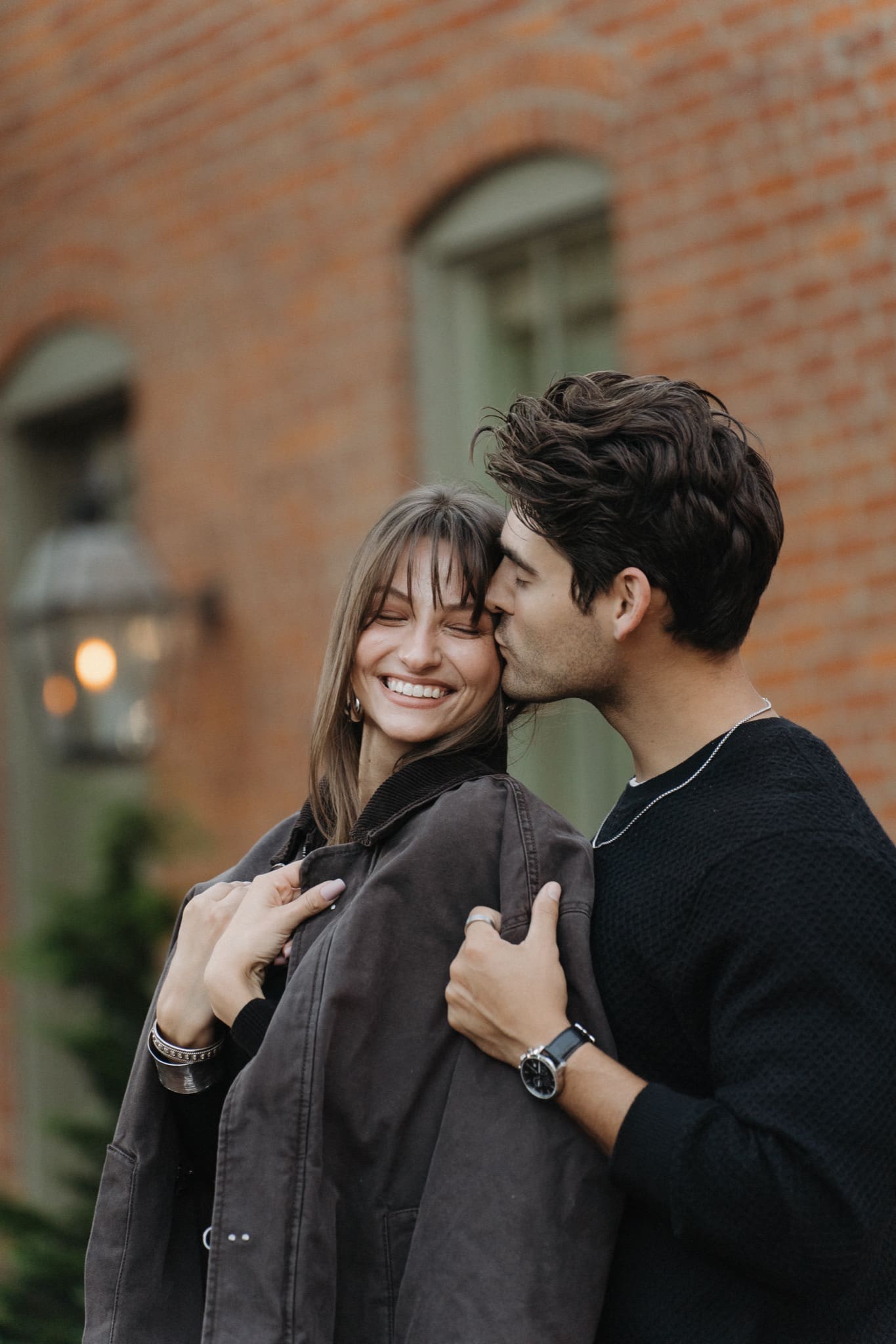 Man kissing his fiancée's cheek beside a gas lantern on a German Village street in Columbus