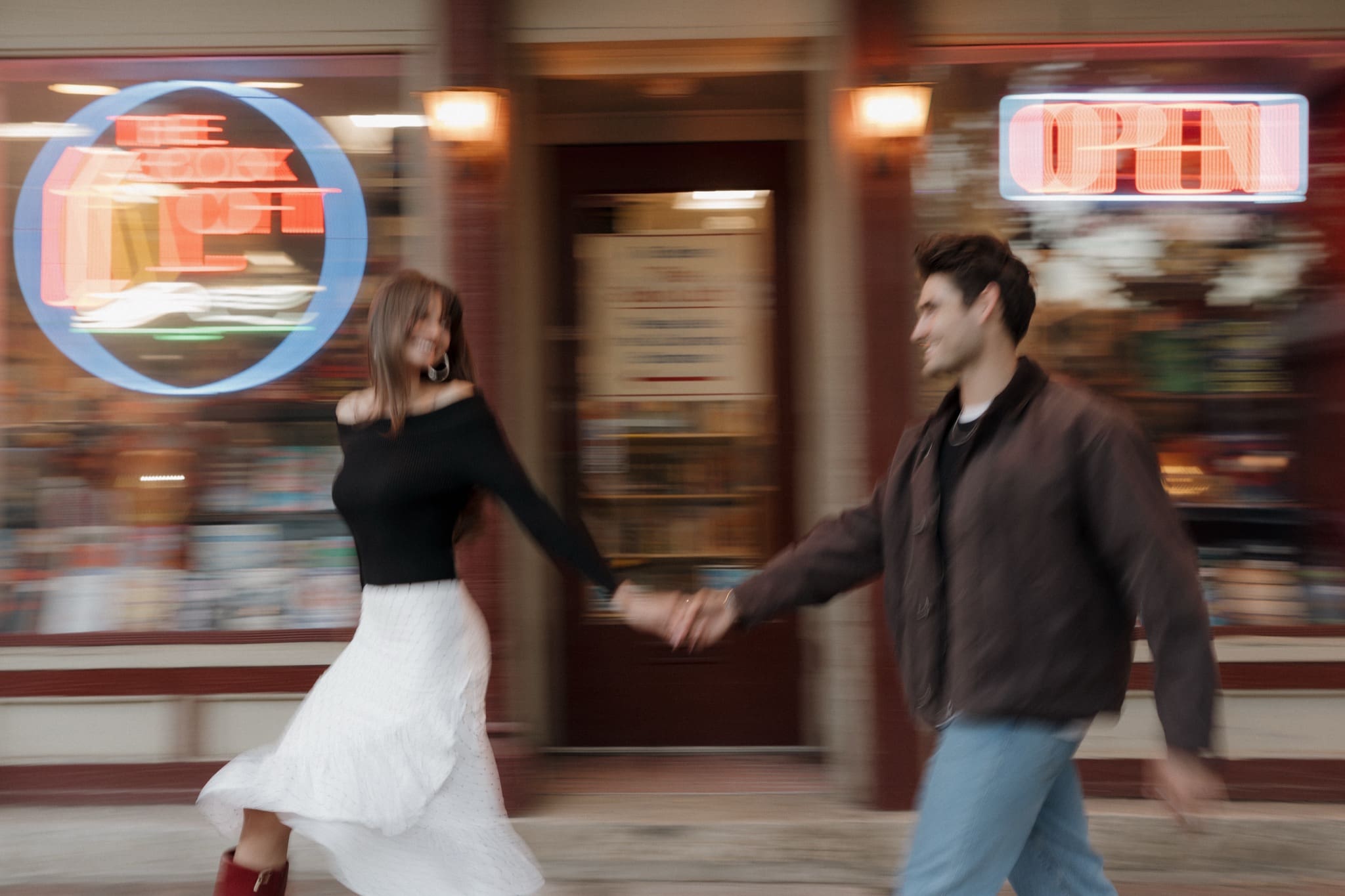 Couple walking hand in hand past The Book Loft's neon sign in German Village, Columbus, Ohio
